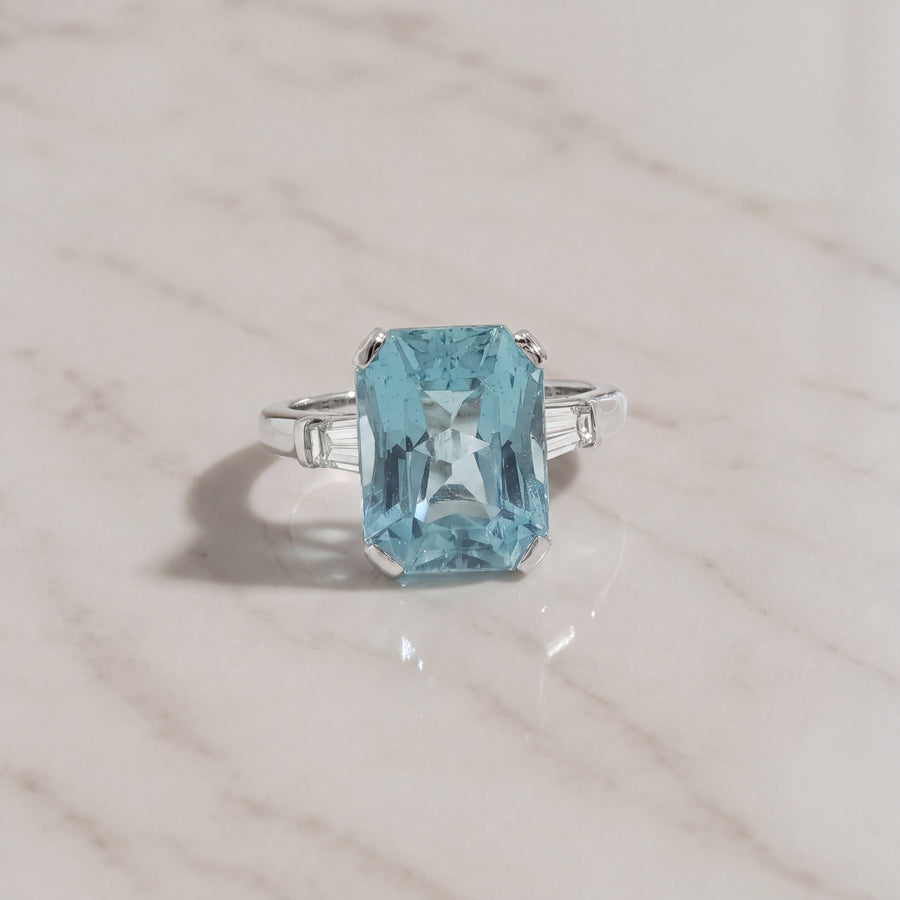 Emerald cut aquamarine ring in four prongs with tapered baguette diamond side stones on a white gold band