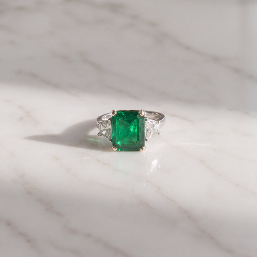 Emerald-cut emerald three-stone ring with trapezoid side diamonds in white gold