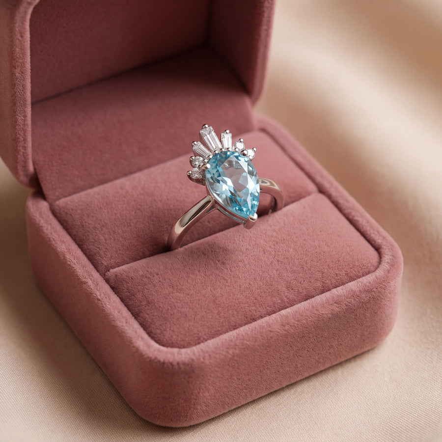 Pear-shaped blue topaz ring crowned with baguette and round diamonds on a plain white gold band
