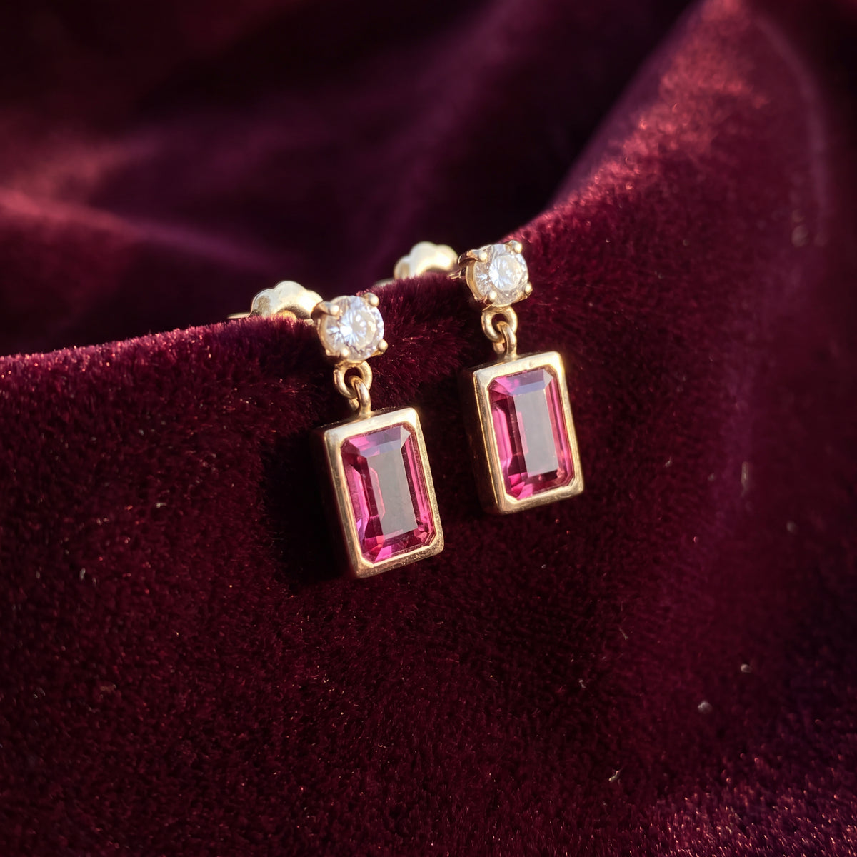 Drop earrings with a rectangular pink stone in a bezel setting below a round white stone stud
