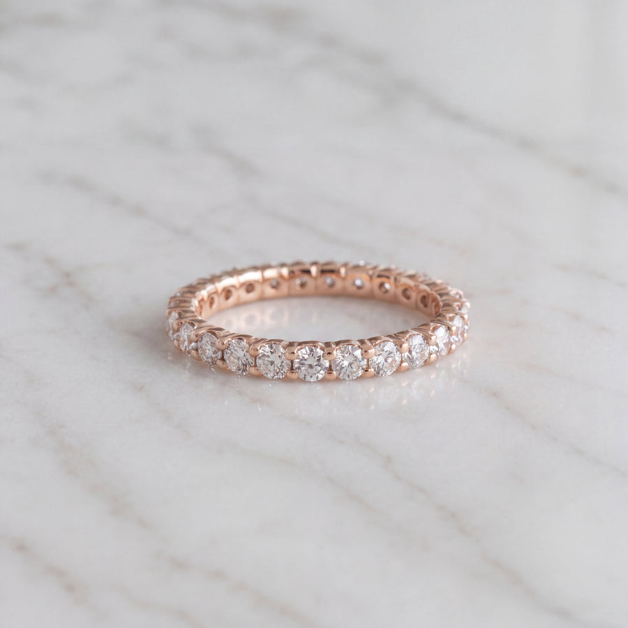 A rose gold eternity ring with round diamonds in shared prongs all the way round.