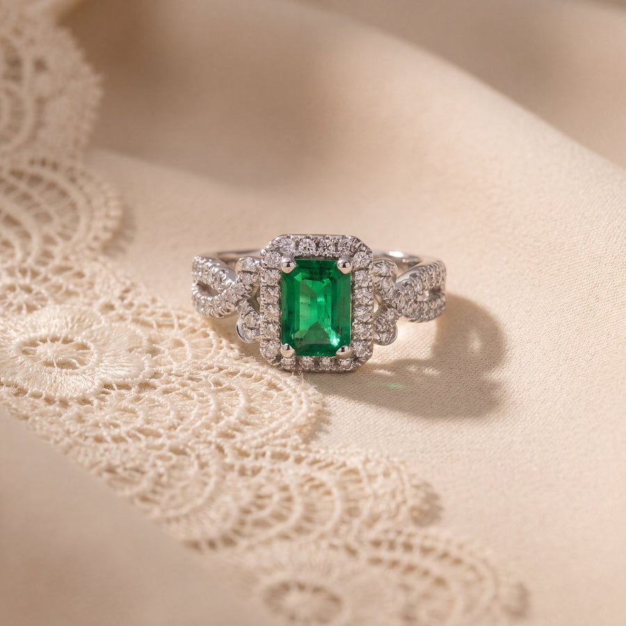 Emerald cocktail ring with a diamond halo and twisted diamond band in white gold