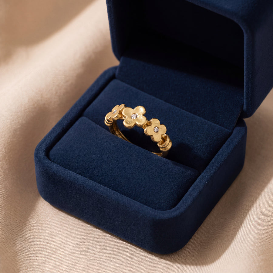 Yellow gold stacking ring with three four-petal flowers, each set with a small round diamond