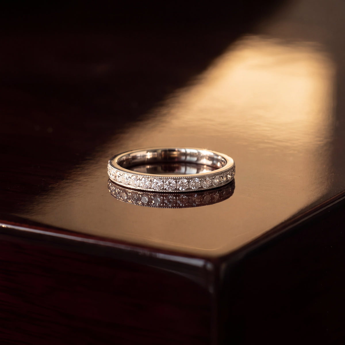 White gold eternity ring with a continuous row of round diamonds framed by milgrain edges