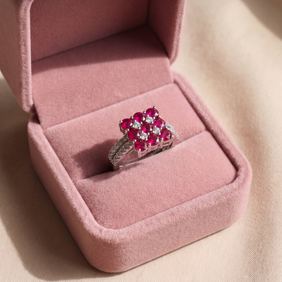 White gold ring with a square cluster of round rubies and diamonds on a split shank