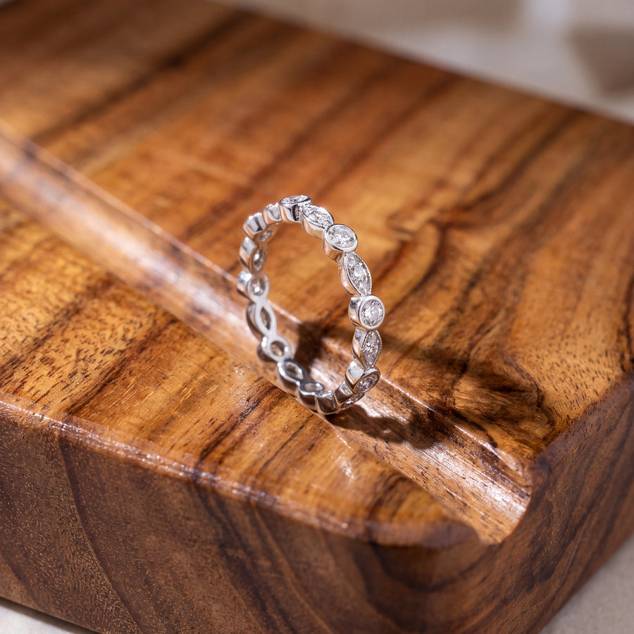 White gold eternity ring alternating bezel-set round diamonds and pavé marquise-shaped settings with milgrain edges