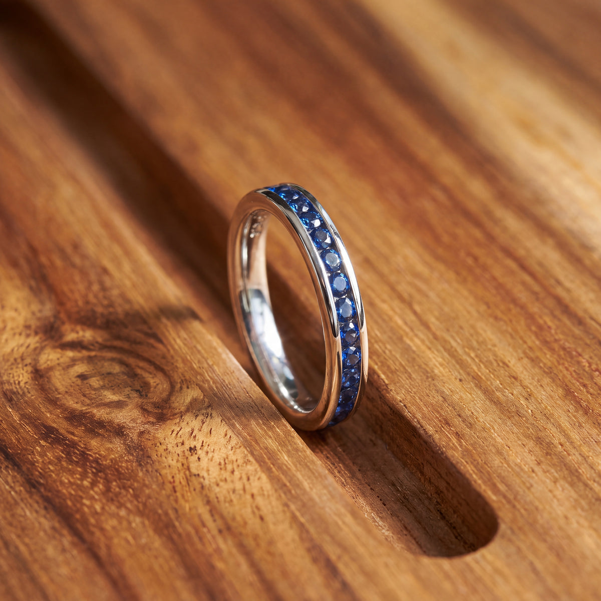 Channel-set band of blue sapphires in polished white gold