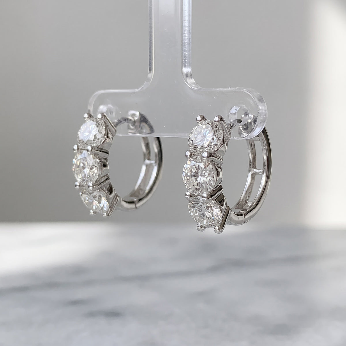 White gold huggie hoop earrings with three round diamonds on each hoop