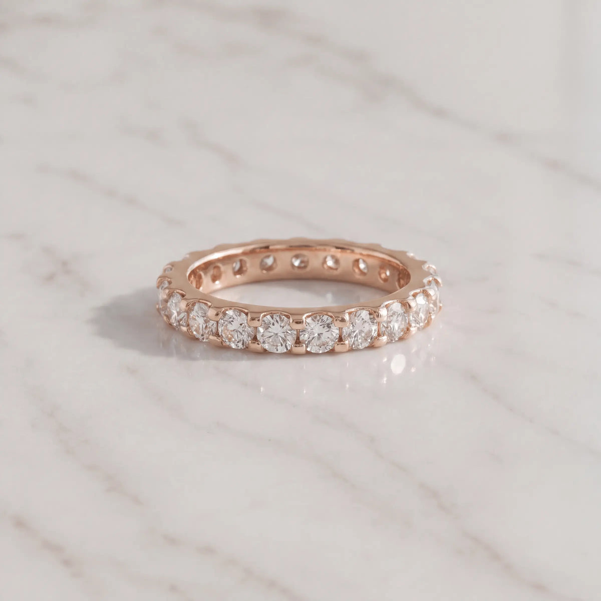A rose-metal diamond band on pale marble