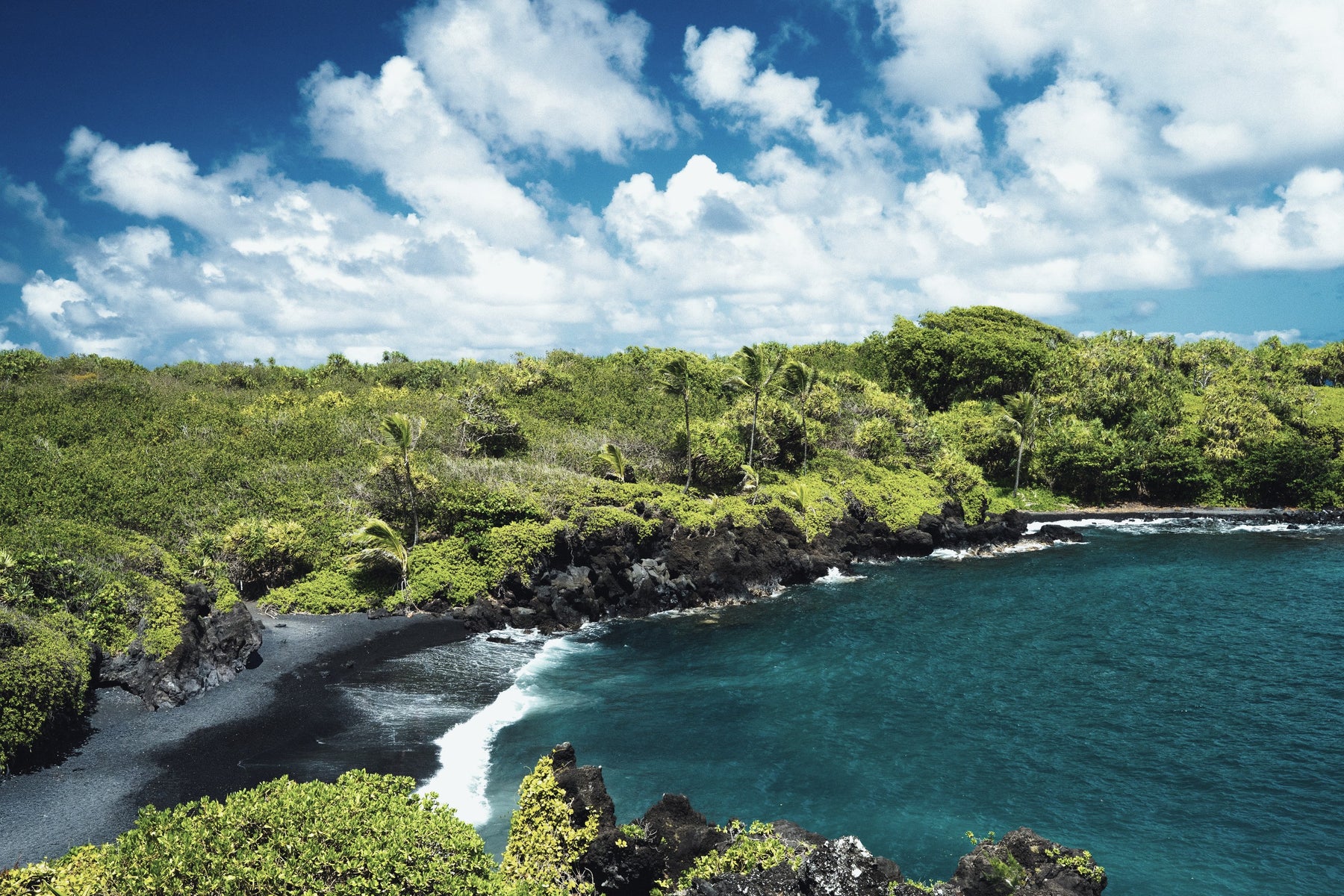 A black sand cove ringed by green cliffs