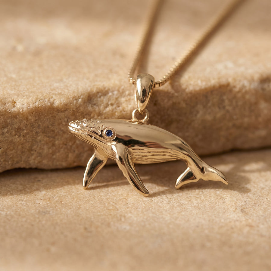 Yellow gold humpback whale pendant with a sapphire eye