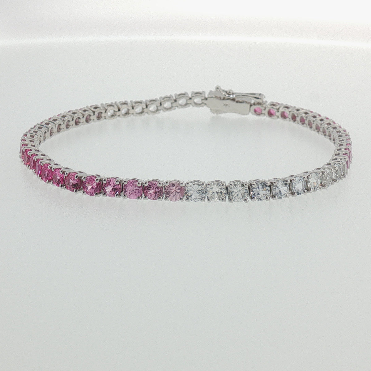 Purplish pink sapphire and diamond tennis bracelet in white gold