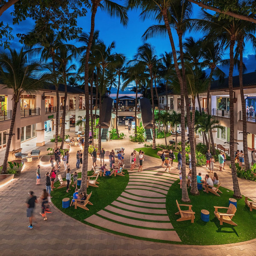 The courtyard at the Shops at Wailea at dusk, the lawn and palms lit under a deep blue sky