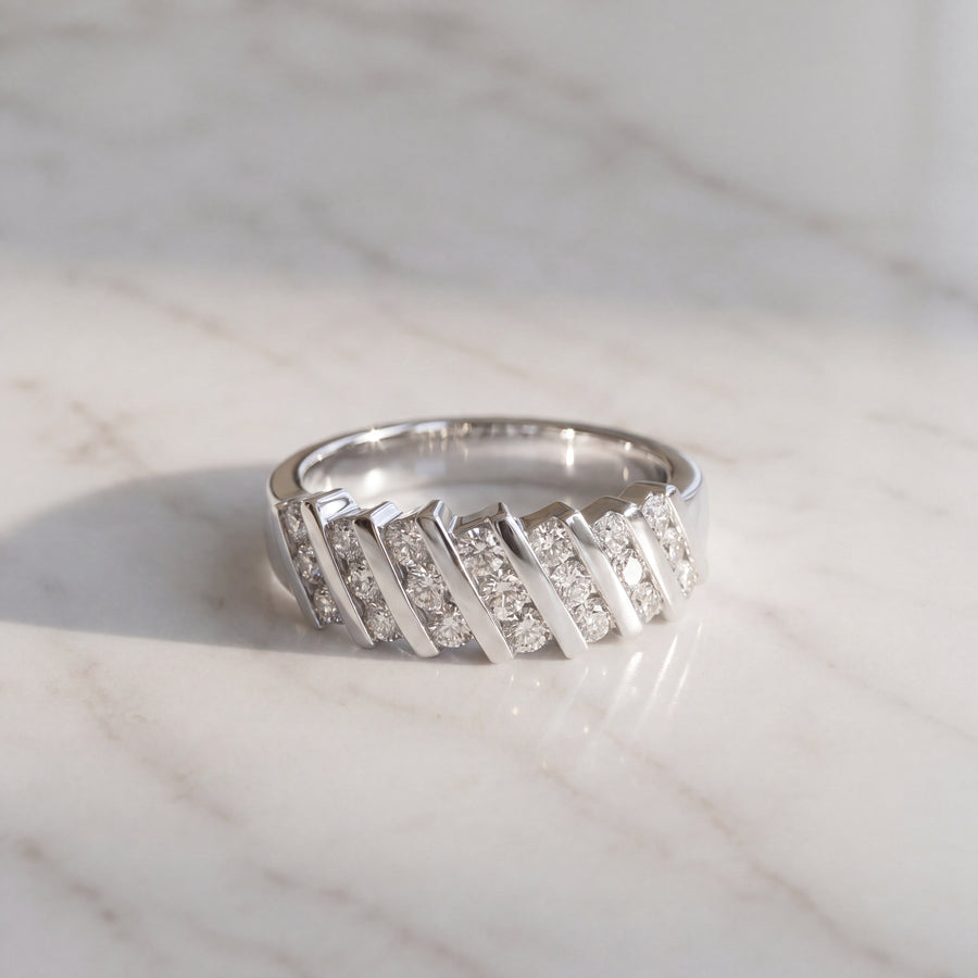 A white gold band with diagonal metal bars separating rows of round diamonds.