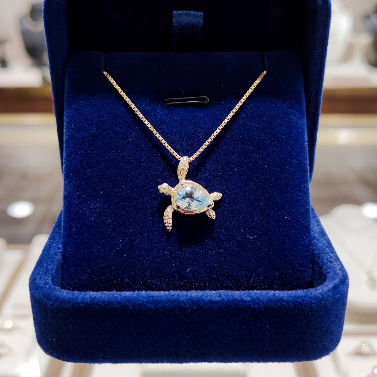 Yellow gold sea turtle pendant with a pear-shaped aquamarine shell on a fine box chain
