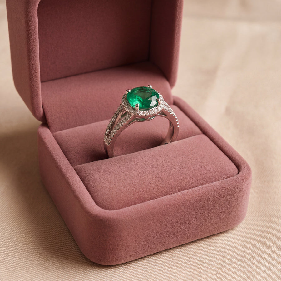 Round green emerald in a diamond halo on a white gold split shank band with pavé diamonds