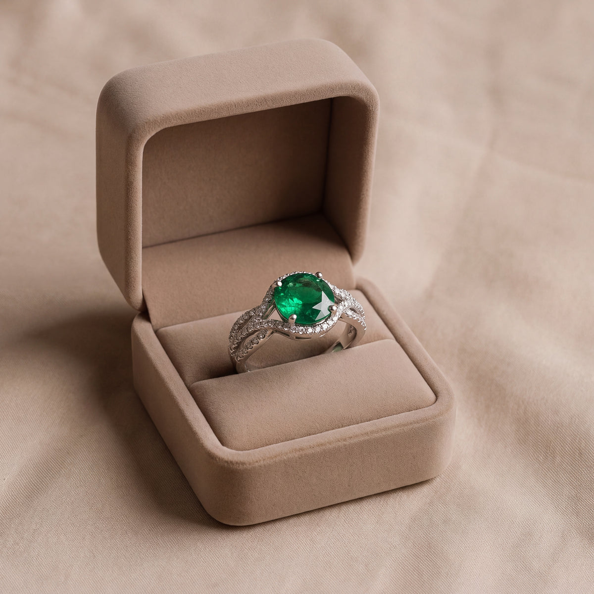 Oval green emerald in a diamond halo on a twisted white gold split shank band set with diamonds