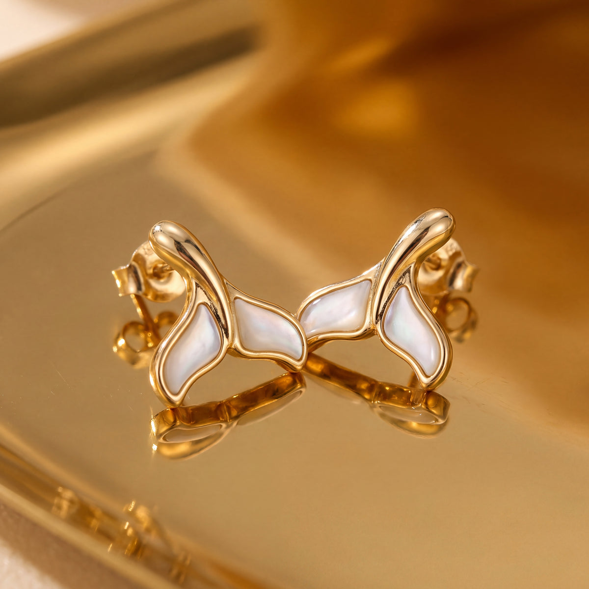 Pair of yellow gold whale tail stud earrings with white mother of pearl inlaid in the flukes