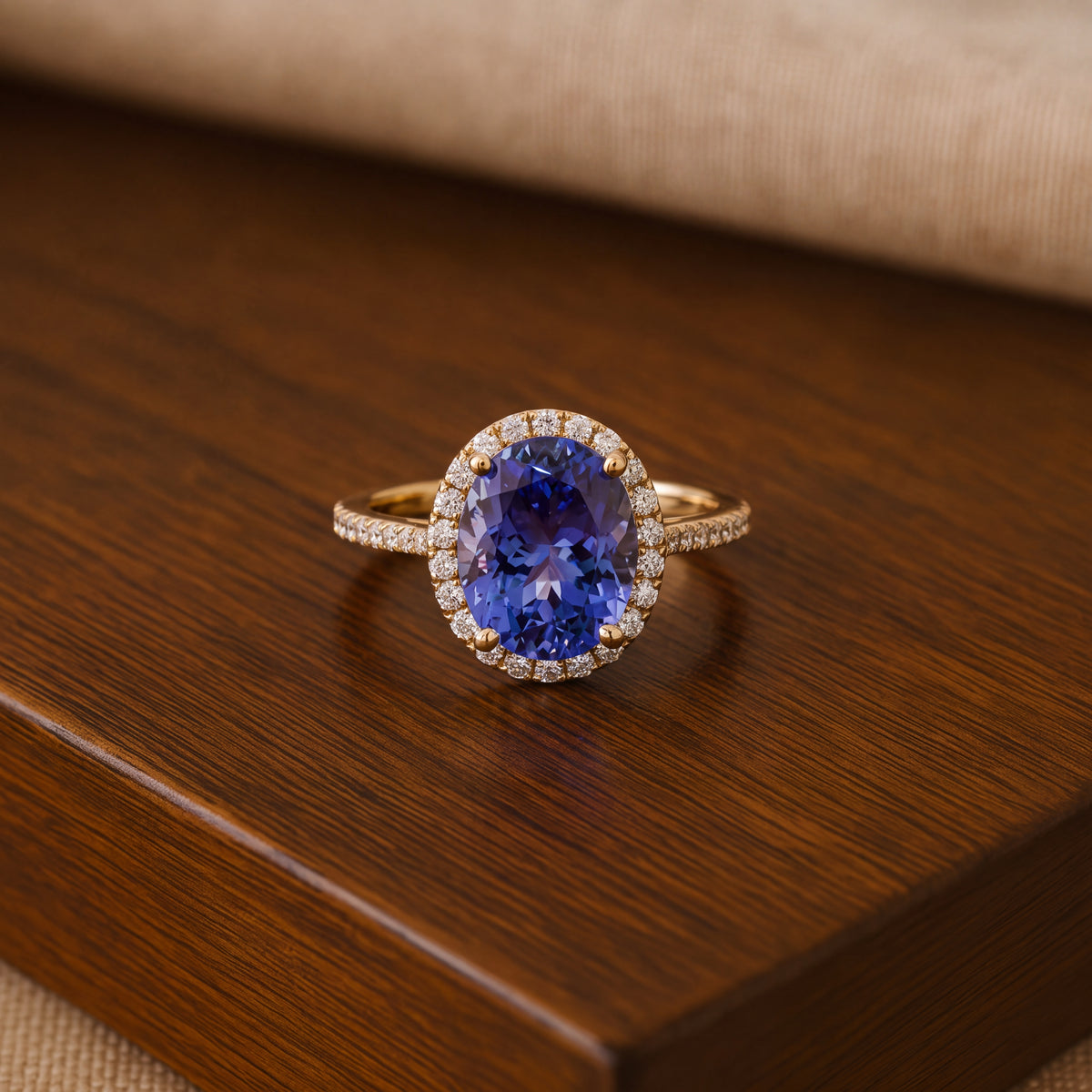 Oval tanzanite in yellow gold prongs and a halo, on a slender yellow gold band