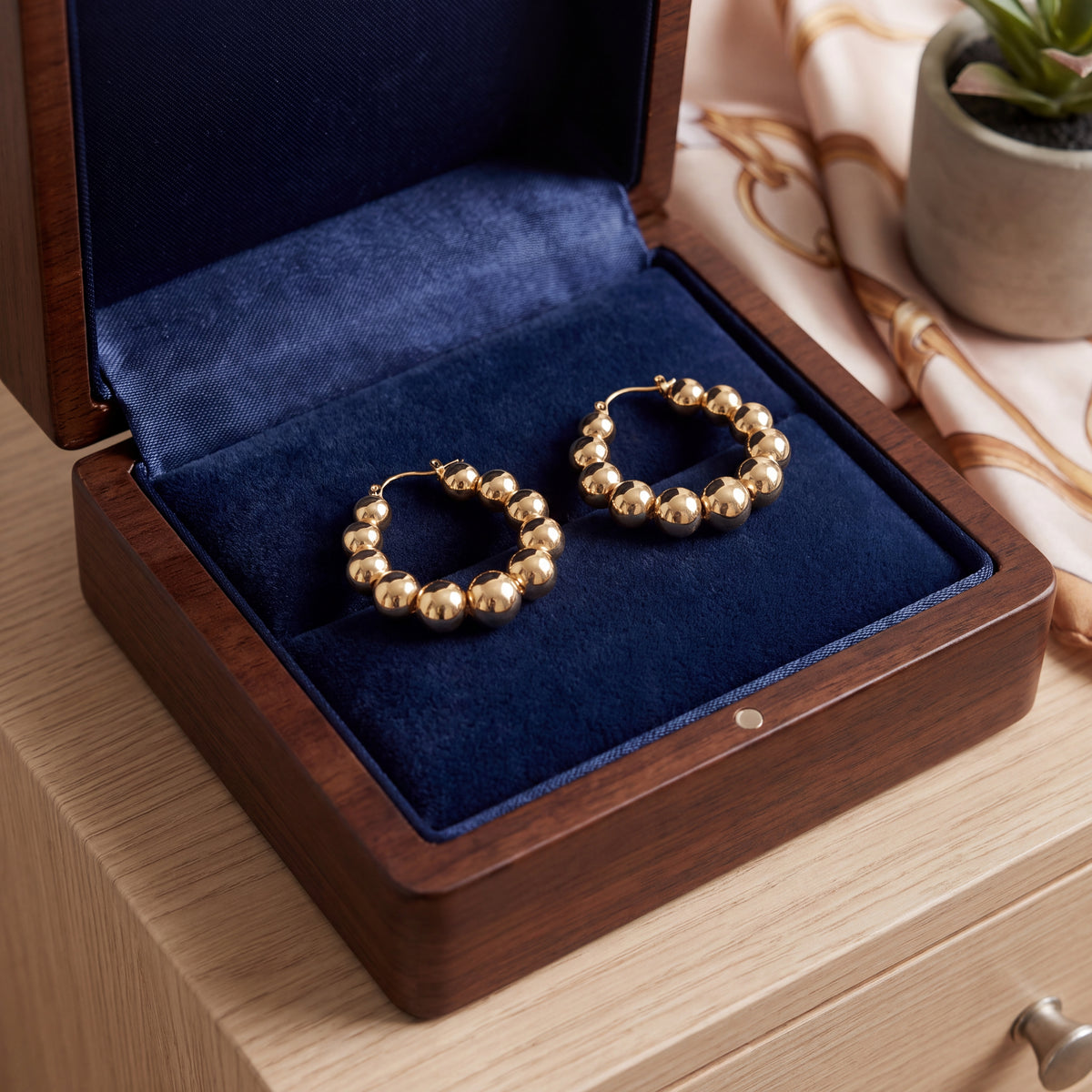 Yellow gold hoop earrings of graduated polished beads