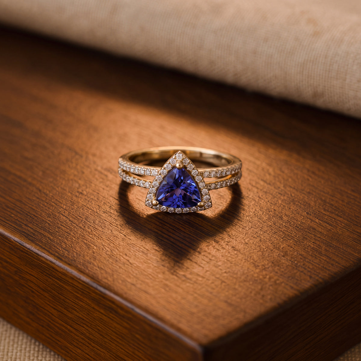 Trillion-cut tanzanite in a diamond halo on a yellow gold split shank