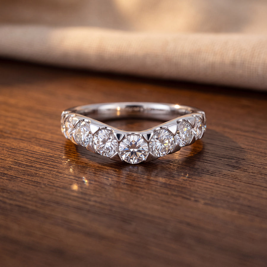 Curved white gold wedding band with a graduated row of round diamonds in shared-prong settings