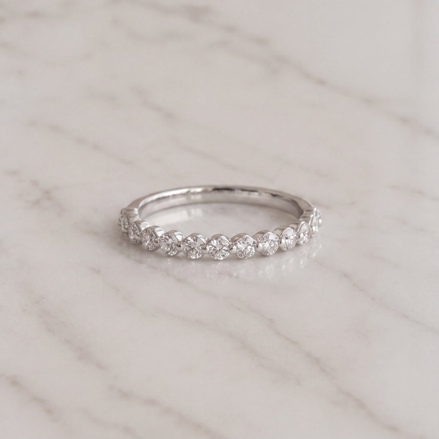 A slender white gold band with round diamonds in a low shared-prong setting.