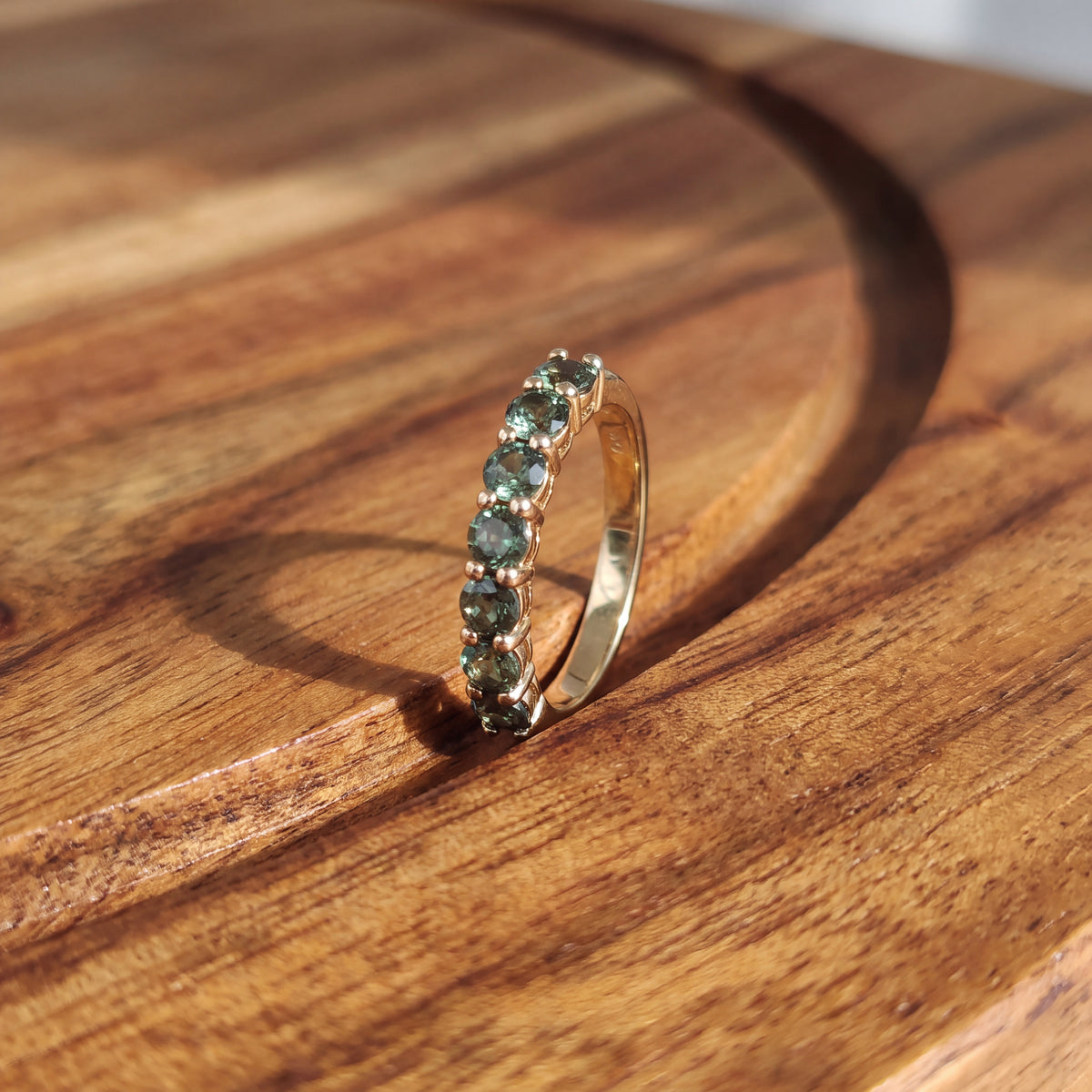 Yellow gold band with a row of round alexandrite gemstones in a shared-prong setting