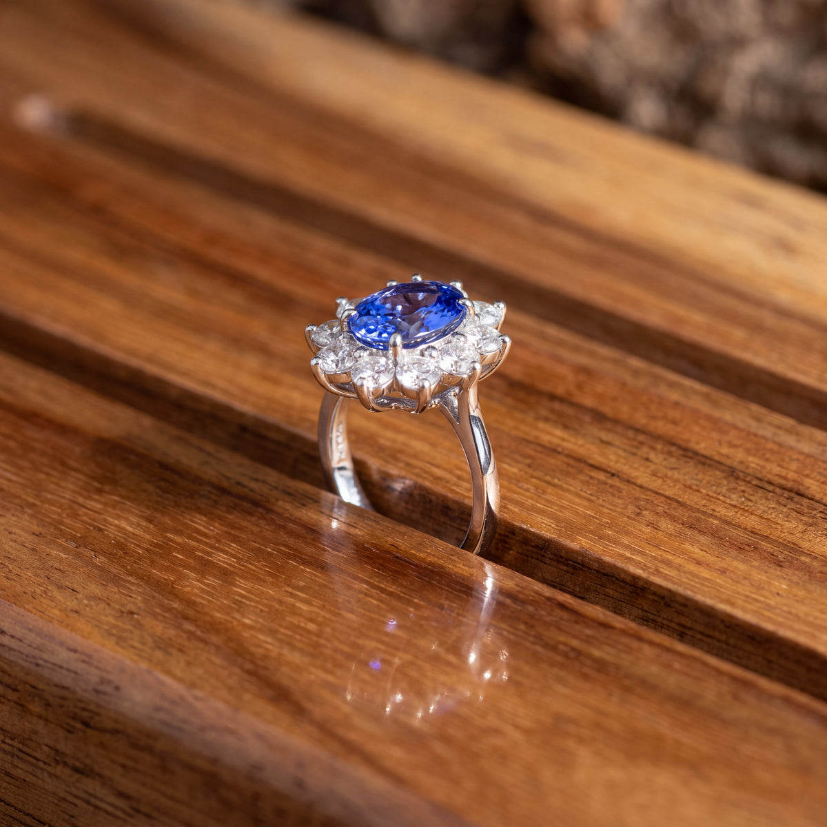 Oval tanzanite in a flower-shaped diamond halo on a white gold band