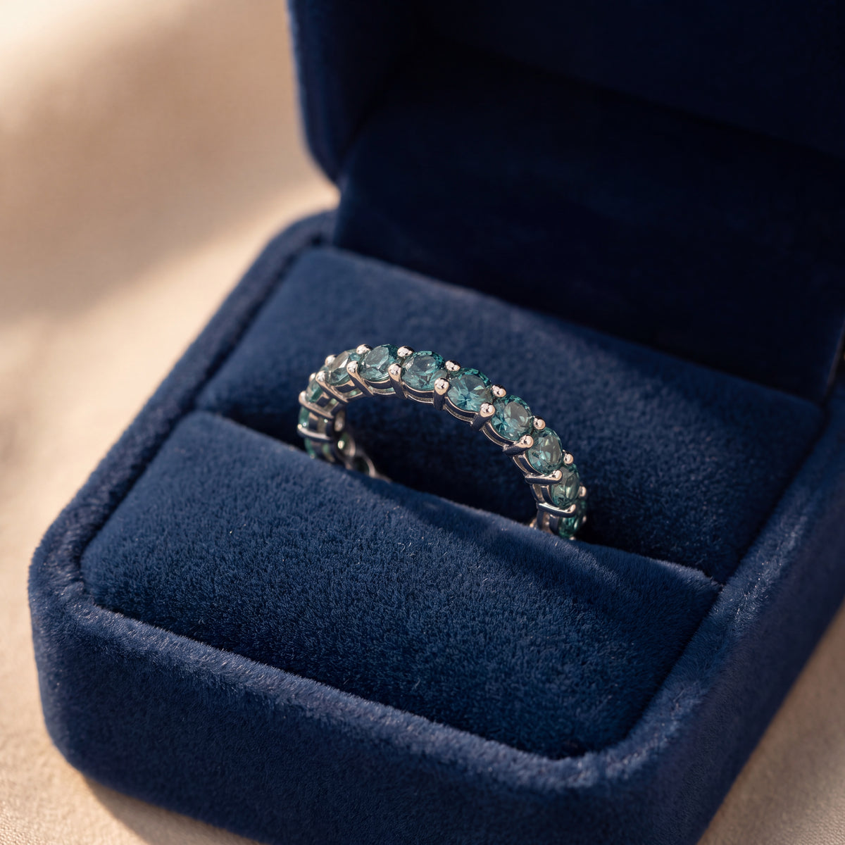 White gold eternity band with round alexandrite gemstones prong-set all the way around