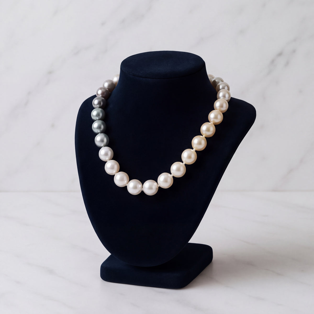 A knotted strand of pearls displayed on a navy velvet bust.