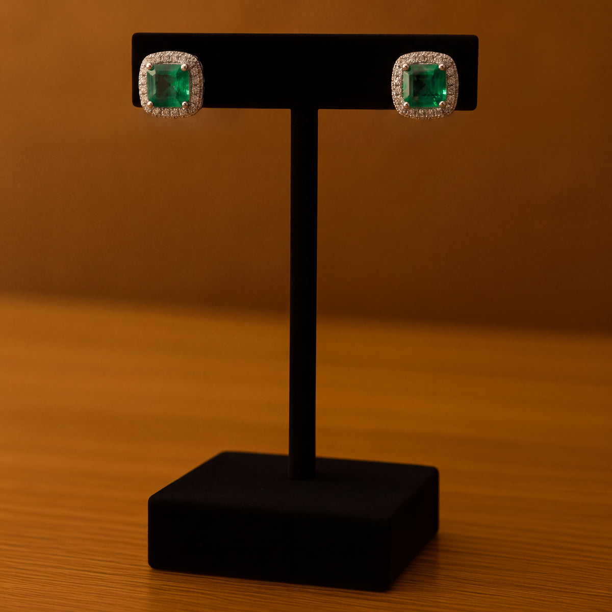 Square-cut emerald stud earrings with diamond halos in white gold