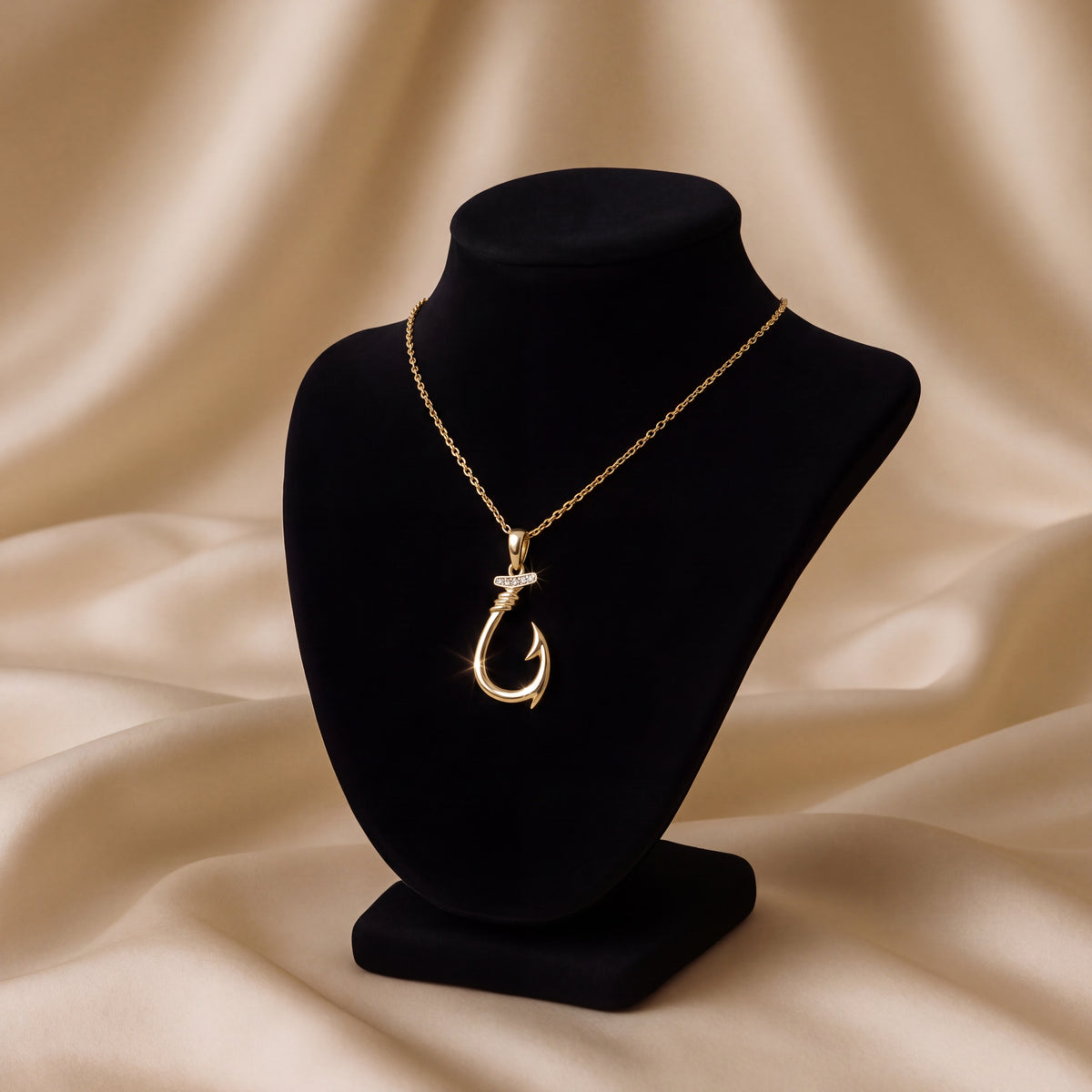 A gold fish hook pendant with diamond accents, on a black velvet bust.