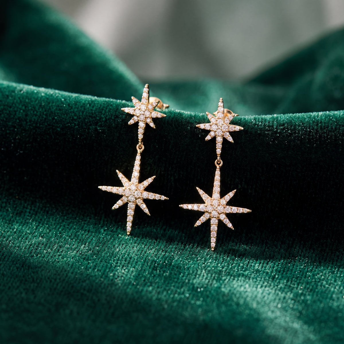 Yellow gold drop earrings of two diamond-set starbursts