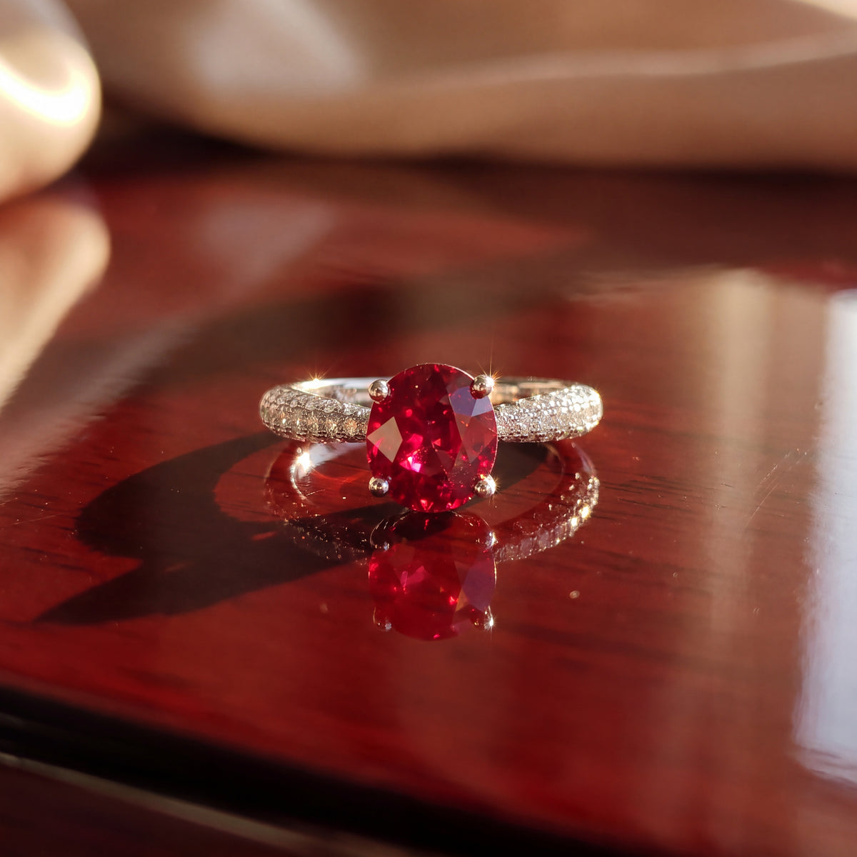 Oval ruby solitaire in four prongs on a white gold pavé band