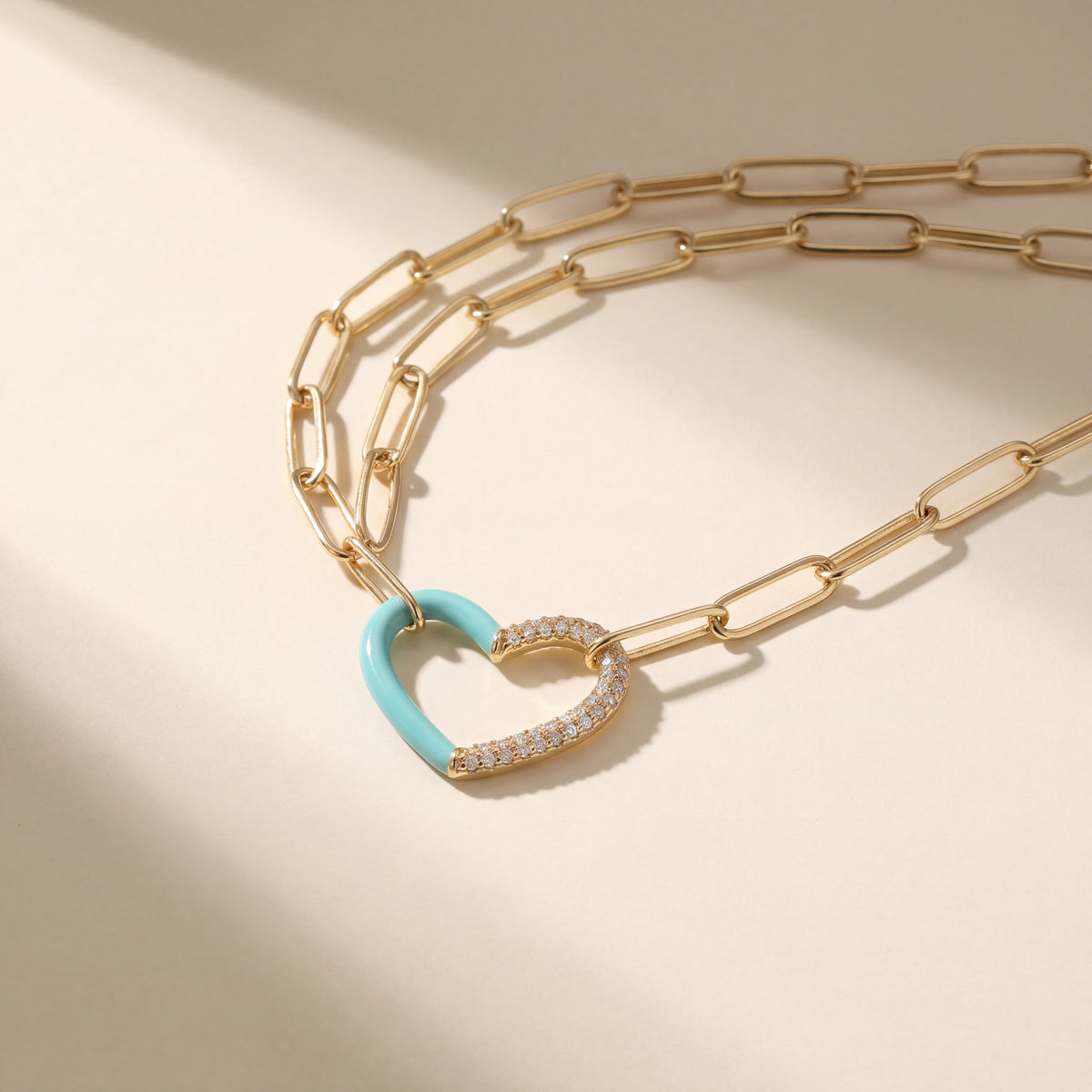 Yellow gold paperclip chain necklace with an open heart, one half teal and the other half pave-set diamonds