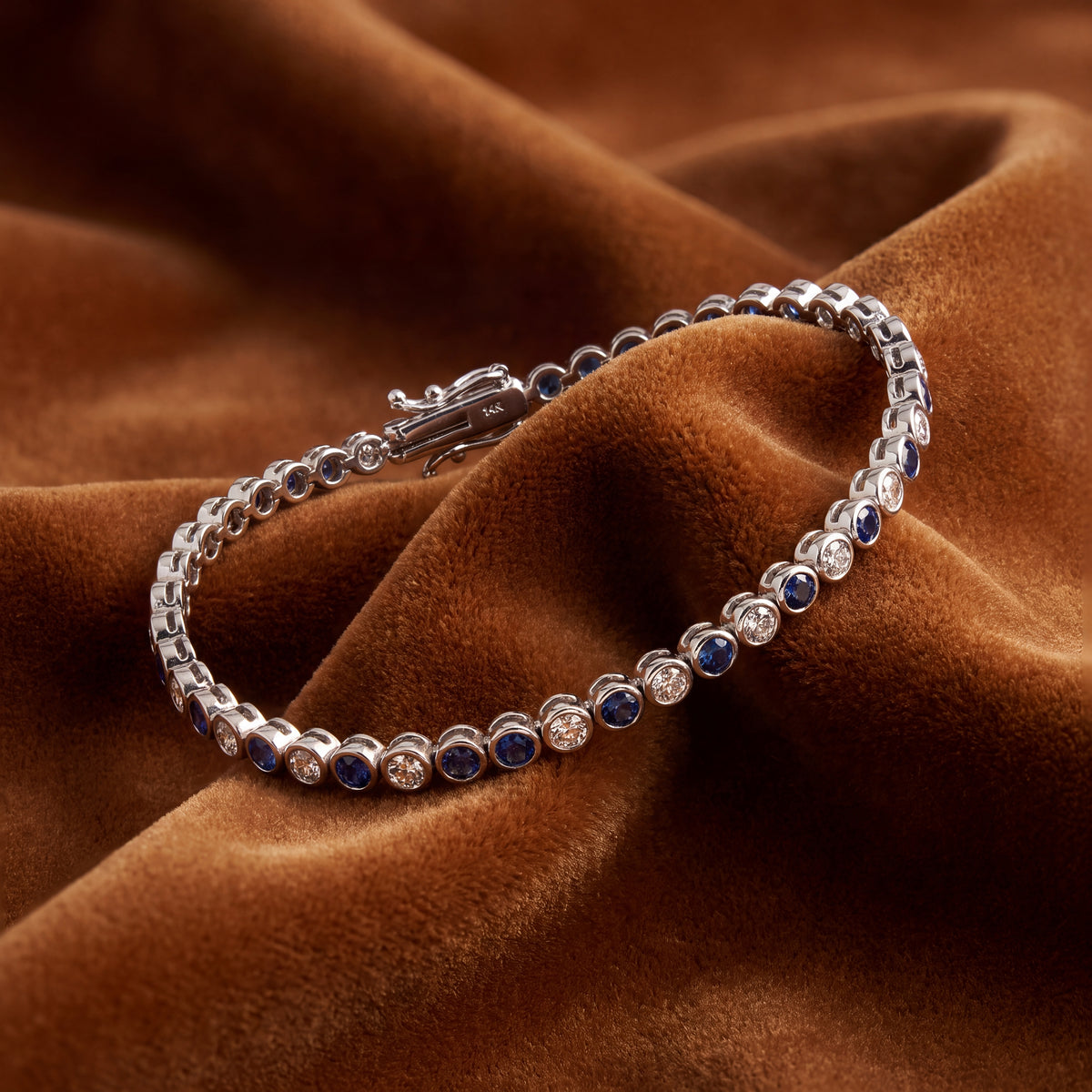 White gold tennis bracelet of bezel-set sapphires and white stones