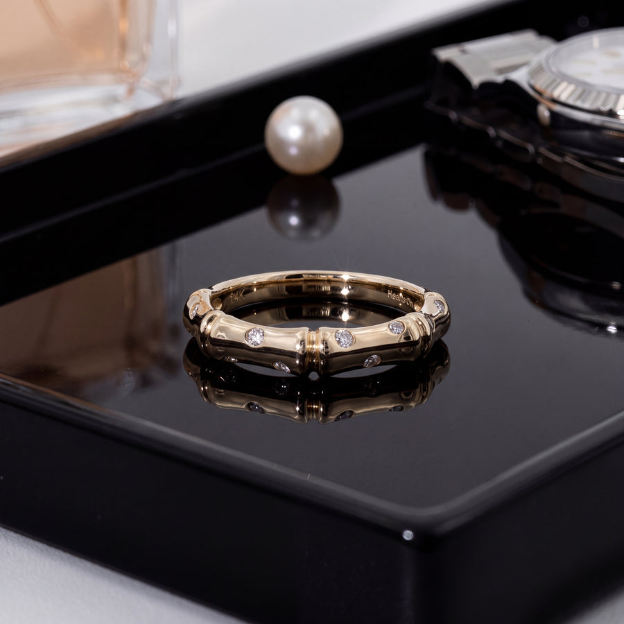 Bamboo-style 14K yellow gold band ring with small round diamonds flush-set between the segments