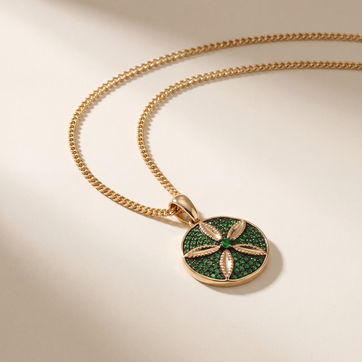 Round yellow gold sand dollar pendant set with green tsavorites