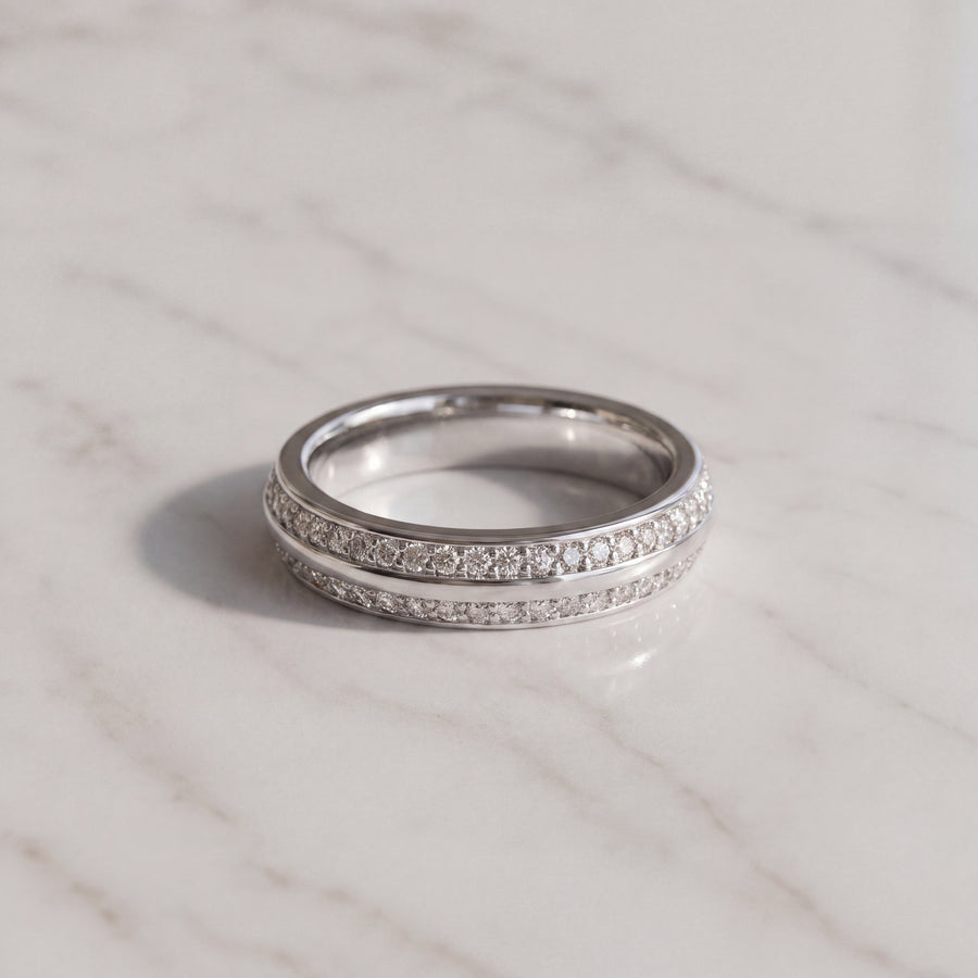 A white gold knife-edge band with two rows of pave diamonds split by a metal ridge.