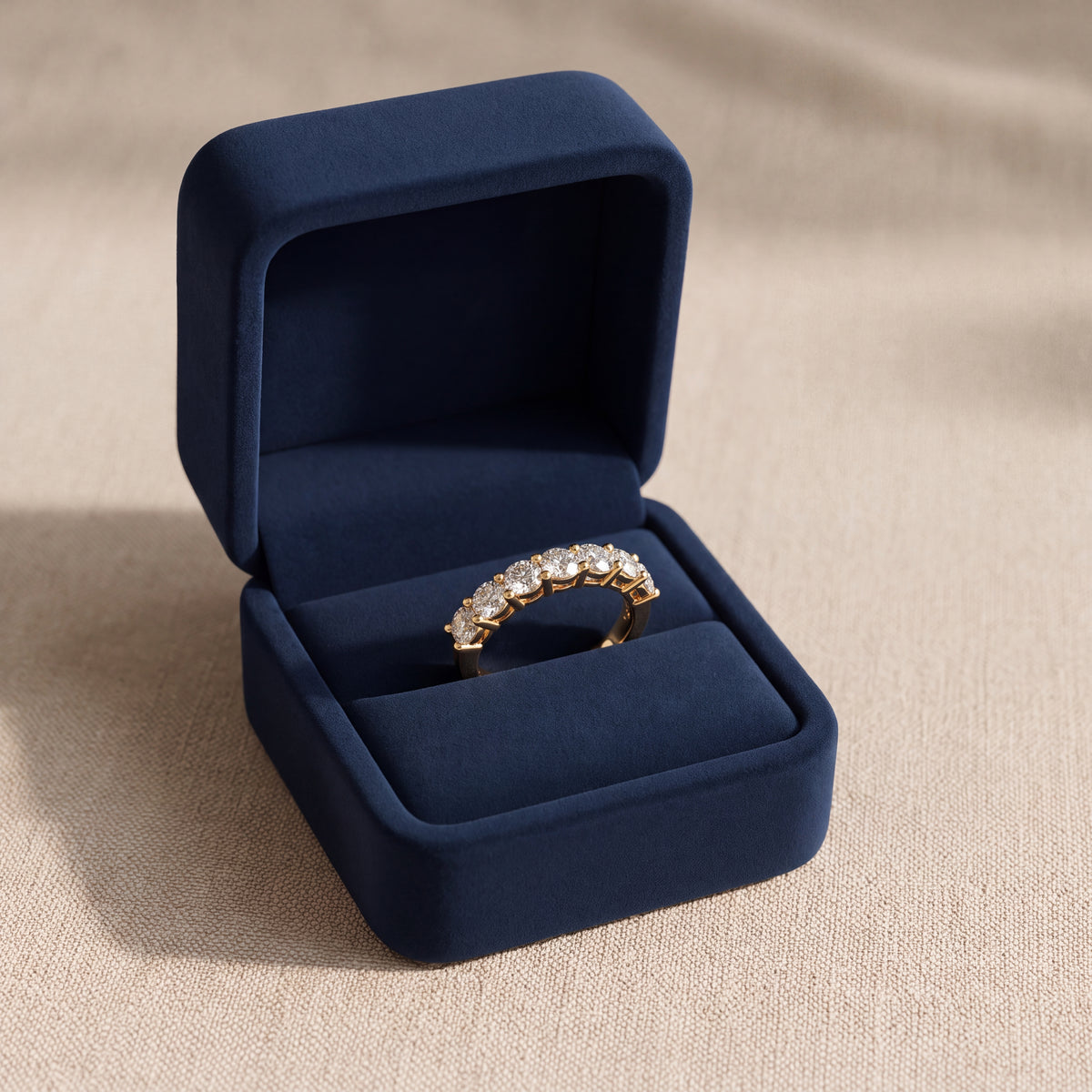 Row of larger round diamonds in shared prongs on a yellow gold band