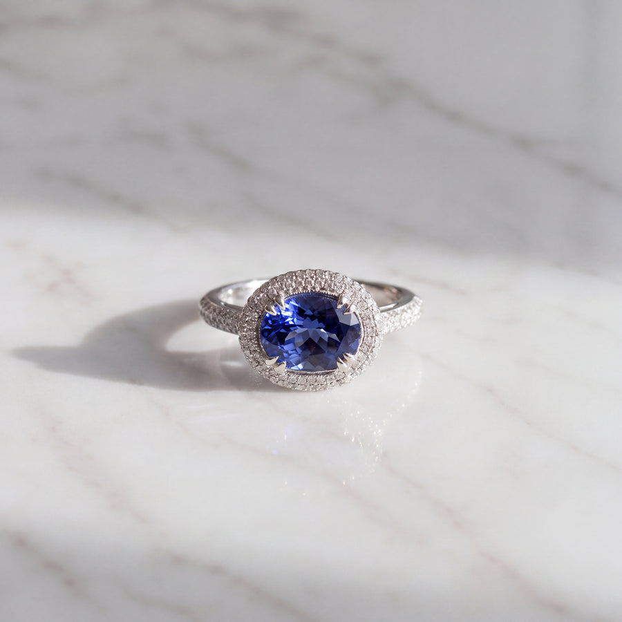 Oval tanzanite cocktail ring in white gold with a diamond pave halo and pave shoulders