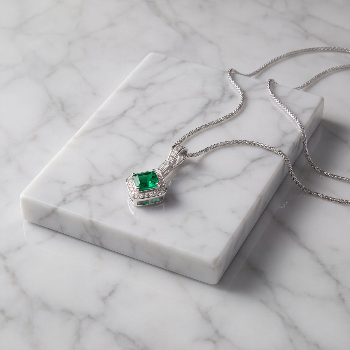 Square-cut emerald pendant with a diamond halo and baguette diamond bail in white gold