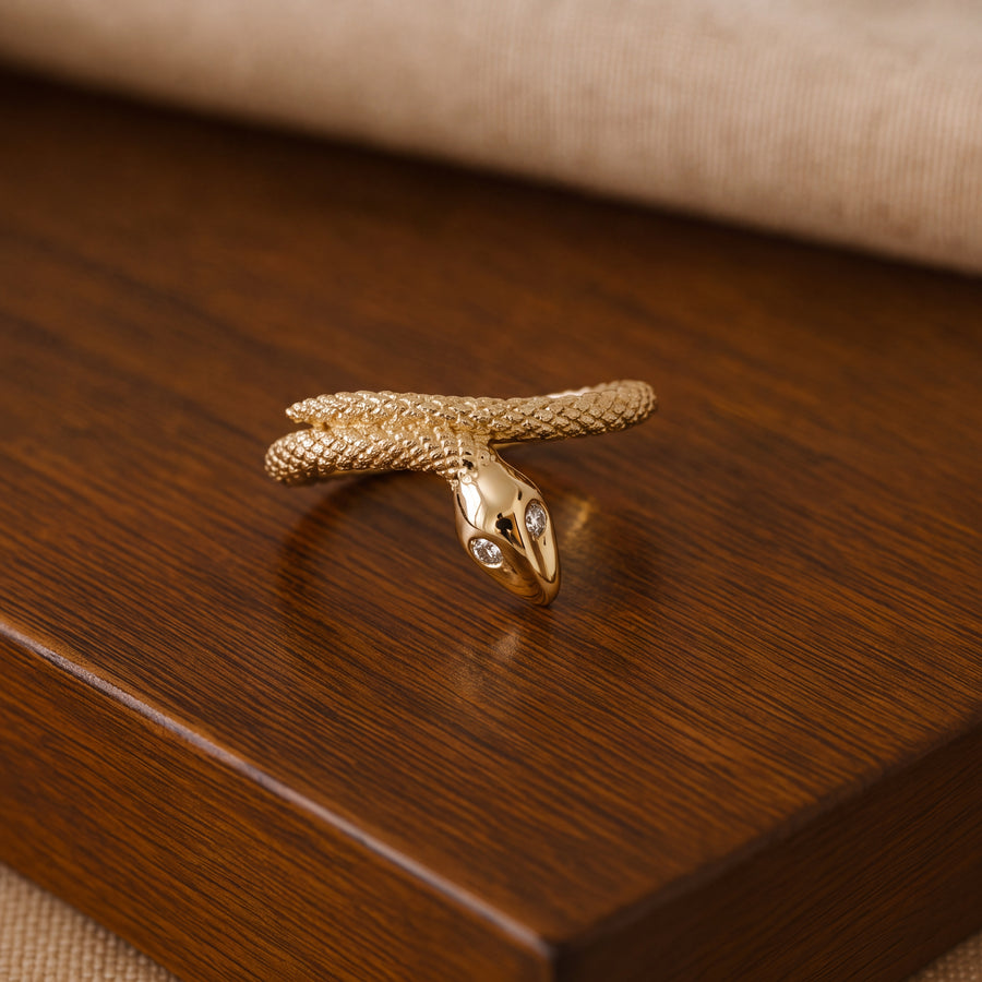 Yellow gold coiled snake wrap ring with a scaled body and two diamond eyes