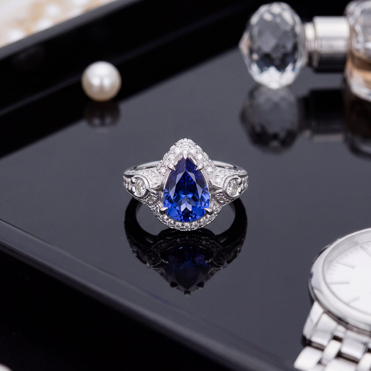 Pear-shaped tanzanite in a diamond halo with detailed white gold shoulders