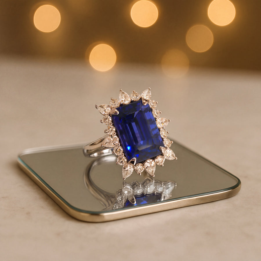 Cocktail ring with a rectangular step-cut tanzanite in a starburst halo of pear and round diamonds, set in white gold
