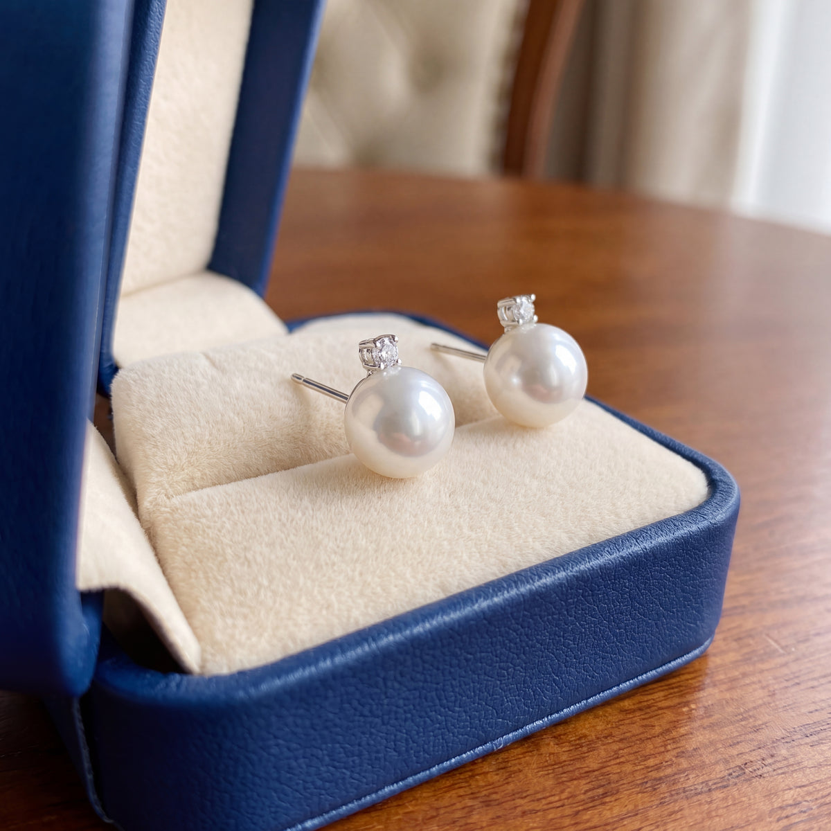 White pearl stud earrings with a small diamond above each