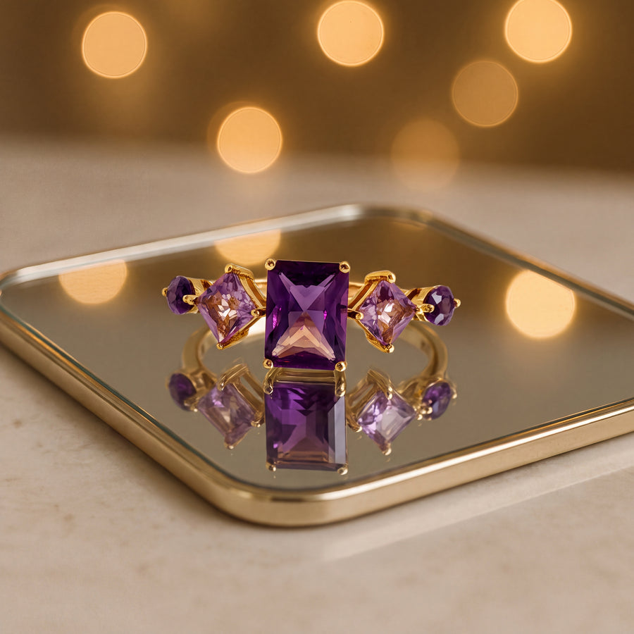 Multi-stone ring with a rectangular step-cut amethyst flanked by square and marquise amethysts in 14K yellow gold