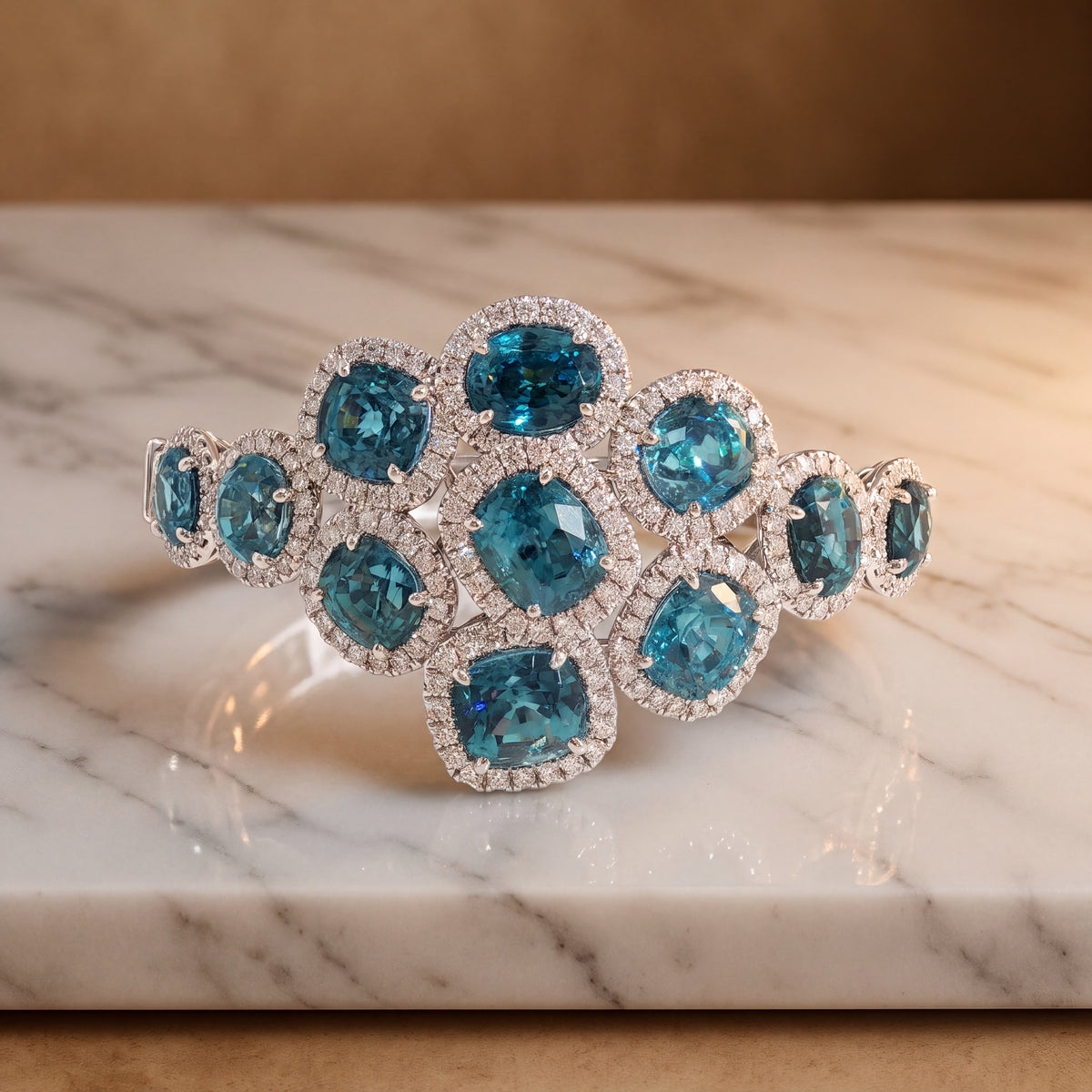 Bangle bracelet with a cluster of oval and cushion-cut blue zircons in diamond halos in white gold