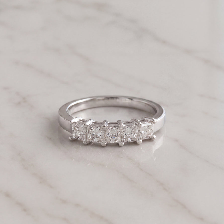 Five princess-cut diamonds in shared prongs across a polished white gold band.